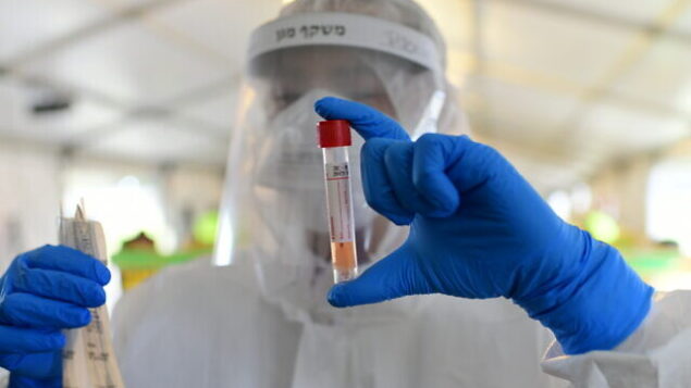 Magen David Adom workers wear protective clothing seen at a drive-through site to collect samples for coronavirus testing, in Tel Aviv, on March 20, 2020. Photo by Tomer Neuberg/Flash90
*** Local Caption *** ÷åøåðä
åéøåñ
áãé÷ä
ñò
áãé÷åú
ðééãåú
çðéåï
áåã÷éí
îâï ãåã àãåí
çåìéí Magen David Adom workers wear protective clothing seen at a drive-through site to collect samples for coronavirus testing, in Tel Aviv, on March 20, 2020. Photo by Tomer Neuberg/Flash90
*** Local Caption *** ÷åøåðä
åéøåñ
áãé÷ä
ñò
áãé÷åú
ðééãåú
çðéåï
áåã÷éí
îâï ãåã àãåí
çåìéí