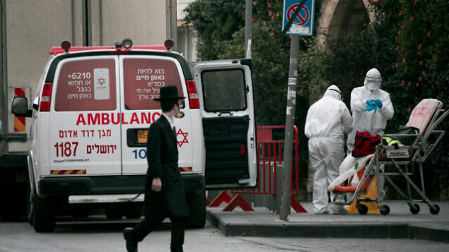 Magen David Adom paramedics, wearing protective clothing as a preventive measure against the coronavirus leave the scene of an emergency call in Jerusalem on March 28, 2020. The government ordered on a partial lockdown, in order to prevent the spread of the Coronavirus. Photo by Olivier Fitoussi/Flash90 Magen David Adom paramedics, wearing protective clothing as a preventive measure against the coronavirus leave the scene of an emergency call in Jerusalem on March 28, 2020. The government ordered on a partial lockdown, in order to prevent the spread of the Coronavirus. Photo by Olivier Fitoussi/Flash90