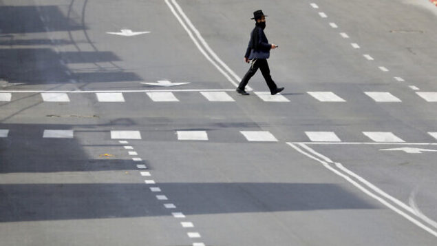 An Ultra orthodox man cross a main deserted street because of the government's measures to help stop the spread of the coronavirus in the orthodox city of Bnei Brak, a Tel Aviv suburb, Israel, Thursday, April 2, 2020. On Wednesday, Netanyahu ordered a police cordon around the largely ultra-Orthodox city of Bnei Brak, east of Tel Aviv, to limit movement to and from the city. Bnei Brak has the second highest number of coronavirus cases in Israel. (AP Photo/Ariel Schalit) An Ultra orthodox man cross a main deserted street because of the government's measures to help stop the spread of the coronavirus in the orthodox city of Bnei Brak, a Tel Aviv suburb, Israel, Thursday, April 2, 2020. On Wednesday, Netanyahu ordered a police cordon around the largely ultra-Orthodox city of Bnei Brak, east of Tel Aviv, to limit movement to and from the city. Bnei Brak has the second highest number of coronavirus cases in Israel. (AP Photo/Ariel Schalit)