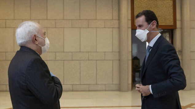 In this photo released by the Syrian official news agency SANA, Syrian President Bashar Assad, right, wears a mask to help protect from the coronavirus, as he speaks with Iranian Foreign Minister Mohammad Javad Zarif, who also wore a mask and gloves, in Damascus, Syria, Monday, April. 20, 2020. (SANA via AP) In this photo released by the Syrian official news agency SANA, Syrian President Bashar Assad, right, wears a mask to help protect from the coronavirus, as he speaks with Iranian Foreign Minister Mohammad Javad Zarif, who also wore a mask and gloves, in Damascus, Syria, Monday, April. 20, 2020. (SANA via AP)