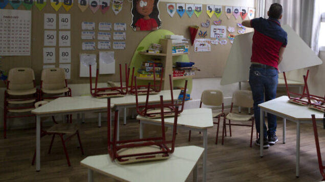 An Israeli parent helps prepare a classroom for the reopening of an elementary school in Tel Aviv, Israel, Thursday, April 30, 2020. Israel is considering reopening some elementary school classes starting Sunday. (AP Photo/Sebastian Scheiner)