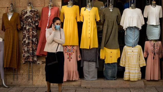 A woman wearing a protective face mask walks past a clothes shop in Jerusalem on April 26, 2020. Photo by Nati Shohat/Flash90