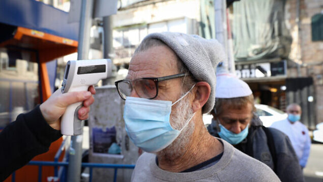 A man checks the temperature of a customer to identify if he have fever at the entrance to the Mahane Yehuda market in Jerusalem, which have been reopened according to the new government orders, May 7, 2020. Photo by Olivier Fitoussi/Flash90 *** Local Caption *** הפגנה
שוק מחנה יהודה
ירושלים
כלכלה