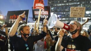 Israelis lift placards and chant slogans during a demonstration in Rabin Square in the central coastal city of Tel Aviv, on July 11, 2020, to protest the government's abandonment of the country's self-employed and other sectors after forcing their businesses to close under COVID-19 regulations, according to the organizers. (Photo by Jack GUEZ / AFP)