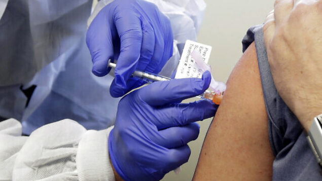 FILE - In this March 16, 2020, file photo, a subject receives a shot in the first-stage safety study clinical trial of a potential vaccine by Moderna for COVID-19, the disease caused by the new coronavirus, at the Kaiser Permanente Washington Health Research Institute in Seattle. According to results released on Tuesday, July 14, 2020, early-stage testing showed the first COVID-19 vaccine tested in the U.S. revved up people’s immune systems the way scientists had hoped. The vaccine is made by the National Institutes of Health and Moderna Inc. (AP Photo/Ted S. Warren, File) FILE - In this March 16, 2020, file photo, a subject receives a shot in the first-stage safety study clinical trial of a potential vaccine by Moderna for COVID-19, the disease caused by the new coronavirus, at the Kaiser Permanente Washington Health Research Institute in Seattle. According to results released on Tuesday, July 14, 2020, early-stage testing showed the first COVID-19 vaccine tested in the U.S. revved up people’s immune systems the way scientists had hoped. The vaccine is made by the National Institutes of Health and Moderna Inc. (AP Photo/Ted S. Warren, File)