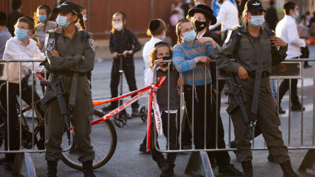 Israeli border police officers stand at a road block as Ultra-Orthodox Jews gather for a protest against lockdown that has been placed in their neighborhood due to a coronavirus outbreak, in Jerusalem, Monday, July 13, 2020. As Israel grapples with a spike in coronavirus cases, it has begun to impose restrictions on selected towns and neighborhoods with high infection rates. Many of these areas are ultra-Orthodox, and residents say they are being unfairly singled out. (AP Photo/Oded Balilty) Israeli border police officers stand at a road block as Ultra-Orthodox Jews gather for a protest against lockdown that has been placed in their neighborhood due to a coronavirus outbreak, in Jerusalem, Monday, July 13, 2020. As Israel grapples with a spike in coronavirus cases, it has begun to impose restrictions on selected towns and neighborhoods with high infection rates. Many of these areas are ultra-Orthodox, and residents say they are being unfairly singled out. (AP Photo/Oded Balilty)