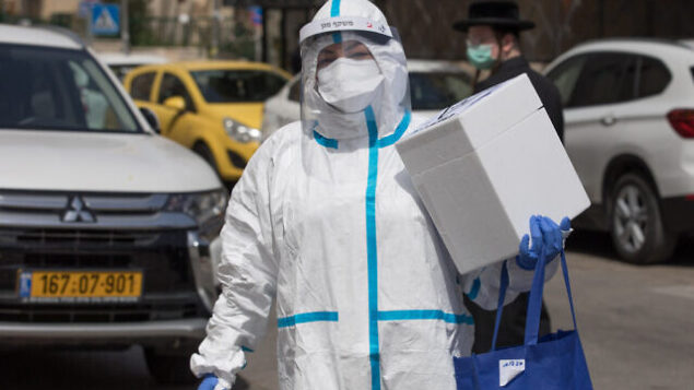 Magen David Adom medical team member, wearing protective gear, is handling a Coronavirus test from patients outside a hotel being used as a coronavirus quarantine facility, in Jerusalem on April 19, 2020. Photo by Nati Shohat/Flash90 *** Local Caption *** קורונה
מגן דוד
אדום
מלון
חולים
קורונה
וירוס
מחלה Magen David Adom medical team member, wearing protective gear, is handling a Coronavirus test from patients outside a hotel being used as a coronavirus quarantine facility, in Jerusalem on April 19, 2020. Photo by Nati Shohat/Flash90 *** Local Caption *** קורונה
מגן דוד
אדום
מלון
חולים
קורונה
וירוס
מחלה