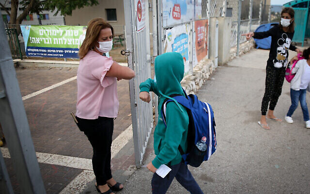 Israeli children wearing face masks make their way to school in Tzfat on their first day back to classes on November 1, 2020, after the government approved the return of grades 1-4 under the Coronavirus restrictions. Photo by David Cohen/Flash90
