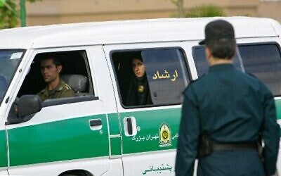 تصویر: در عکسی از ۲۳ ژوئیهٔ ۲۰۰۷، یک مأمور پلیس ایرانی از پشت سر به خودرو پلیس پیش از یورش برای اجرای قوانین حجاب اسلامی در تهران، پایتخت ایران، نگاه می کند. (Behrouz MEHRI/AFP)