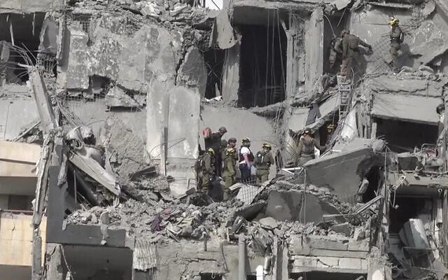 شرح عکس: در عکسی که در شبکهٔ اجتماعی منتشر شد، لحظهٔ اصابت موشک بالستیک ایران در ۲۴ ژوئن ۲۰۲۵ به مجتمع ساختمانی در بئرشبا، جنوب اسرائيل را نشان می دهد. 
(X; used in accordance with Clause 27a of the Copyright Law)
گروه های امداد، در محل، حین جستجو میان ویرانه مشاهده می شوند. 
(Anadolu Agency via Reuters/Jorge Novominsky/AFPTV/AFP)