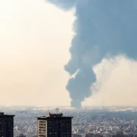 شرح عکس: بعد از بمباران شبانهٔ اسرائيل در ۱۵ ژوئن ۲۰۲۵، انبوه دود بر فراز پالایشگاه نفت جنوب تهران مشاهده می شود. (Photo by Atta KENARE / AFP)