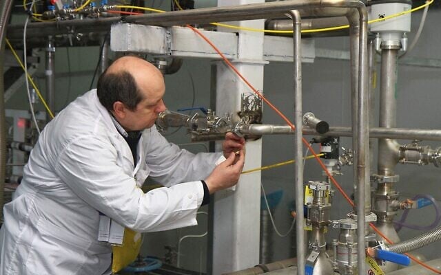 آرشیو: یکی از بازرسان آژانس بین المللی انرژی اتمی (IAEA)، که هویت وی مشخص نشده، در ۲۰ ژانویهٔ ۲۰۱۴، در مرکز تحقیقات هسته ای نطنز، حدود ۳۰۰ کیلومتر جنوب تهران، رابط میان آبشارهای دوقلوی تولید اورانیوم ۲۰ درصدی را قطع می کند. (KAZEM GHANE/IRNA/AFP)