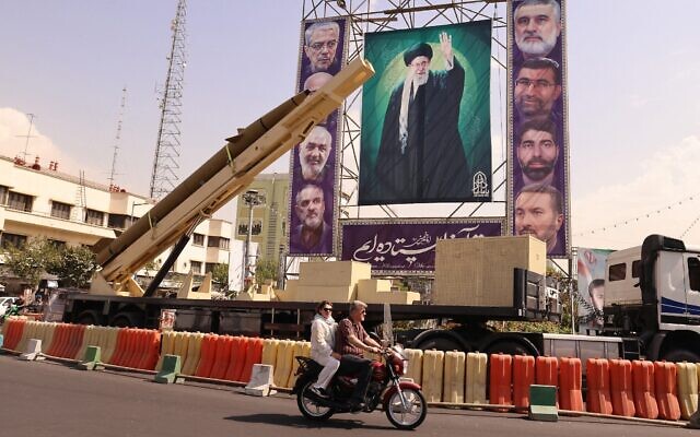 شرح عکس: مردی سوار بر موتورسیکلت از جلو موشک بالستیک غیرفعال خیبرشکن مقابل تصویری از علی خامنه ای ولی فقیه رژیم ایران که در ۲۷ سپتامبر ۲۰۲۵ در «هفتهٔ دفاع مقدس»، به یادبود جنگ ایران و عراق در فاصلهٔ سال های ۱۹۸۰تا ۸۸، میدان بهارستان برپا شد، می گذرد. (ATTA KENARE / AFP)