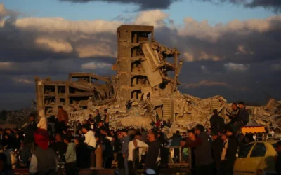 شرح عکس: فلسطینیان آواره کنار خانه های تخریب شدهٔ اردوگاه پناهندگی نصیرات در مرکز نوار غزه ایستاده اند؛ ۱۹ دسامبر ۲۰۲۵. (Eyad Baba / AFP)