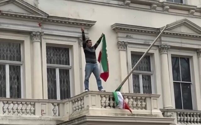 شرح عکس: یک معترض در ۱۰ ژانویهٔ ۲۰۲۶، پرچم جمهوری اسلامی را از سردر سفارت ایران در لندن بر میدارد و به جای آن پرچم پیش از انقلاب را می گذارد. (Photo by Alina Brestnieva) شرح عکس: یک معترض در ۱۰ ژانویهٔ ۲۰۲۶، پرچم جمهوری اسلامی را از سردر سفارت ایران در لندن بر میدارد و به جای آن پرچم پیش از انقلاب را می گذارد. (Photo by Alina Brestnieva)
