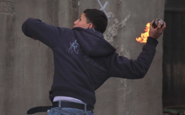 Un Palestinien jette une bombe incendiaire sur des soldats au checkpoint de Qalandiya, près de Ramallah. Photo d'illustration. (Crédit : Issam Rimawi/Flash90)