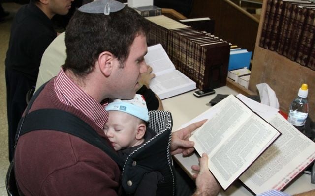 Un père et son bébé alors qu'il étudie la Torah. (Gershon Elinson/Flash90)