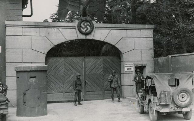 Les troupes américaines postées à l'entrée du camp de concentration de Dachau (Crédit : US National Archives/Wikimedia Commons)
