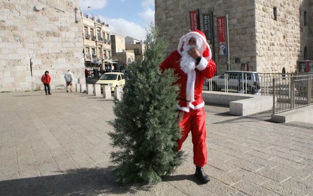Un homme habillé en Père Noël avec un sapin de Noël, porte de Jaffa, devant la Vieille Ville de Jérusalem, en décembre 2008. Illustration. (Crédit : Yossi Zamir/Flash90) Un homme habillé en Père Noël avec un sapin de Noël, porte de Jaffa, devant la Vieille Ville de Jérusalem, en décembre 2008. Illustration. (Crédit : Yossi Zamir/Flash90)
