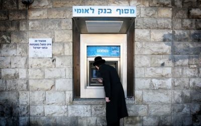 Un homme retire de l'argent d'un distributeur de la banque Leumi dans le quartier de Mea Shearim, à Jérusalem. Illustration. (Crédit : Nati Shohat/Flash90)