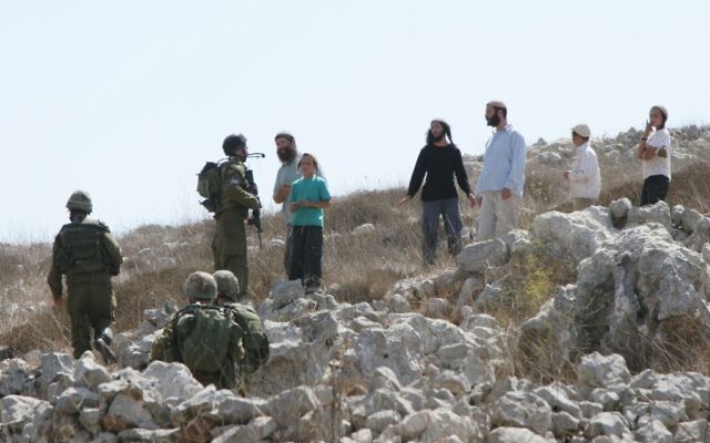 Jewish settlers argue with Israeli soldiers during a dispute between settlers and Palestinians over farming land between the Jewish settlement of Bracha and the nearby West Bank village of Burin, September 21, 2010 (photo credit: Wagdi Ashtiyeh/Flash90)