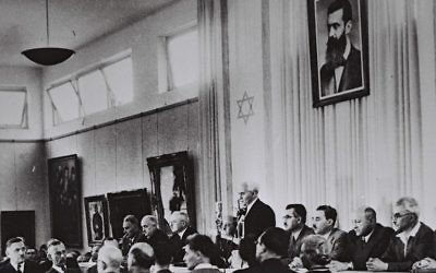 David Ben Gurion, entouré des membres du gouvernement provisoire, proclame la Déclaration d'indépendance dans le hall du musée de Tel Aviv, le 14 mai 1948 (Crédit : bureau de presse du gouvernement israélien)