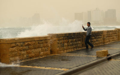 Un homme photographie les vagues à Jaffa (Crédit : Tomer Neuberg/Flash90)