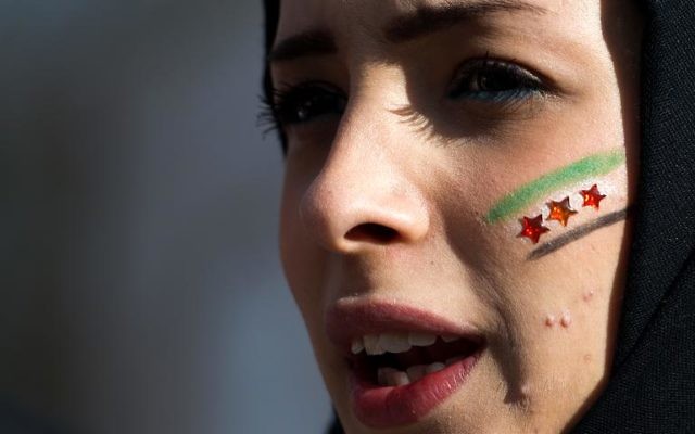 Vendredi 24 janvier 2014, devant le siège de l'Onu à Genève, une manifestante contre le régime de Bachar al-Assad, maquillée aux couleurs nationales syriennes. (Crédit : AFP/Fabrice Coffini) Vendredi 24 janvier 2014, devant le siège de l'Onu à Genève, une manifestante contre le régime de Bachar al-Assad, maquillée aux couleurs nationales syriennes. (Crédit : AFP/Fabrice Coffini)