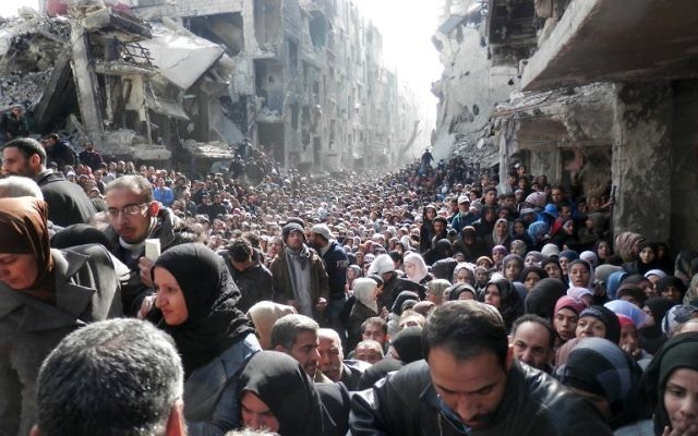 La file interminable de réfugiés lors d'une distribution de nourriture organisée par l'ONU, dans les ruines du camp de réfugiés de Yarmouk, au sud de Damas (Crédit : AFP Photo/HO/UNRWA) La file interminable de réfugiés lors d'une distribution de nourriture organisée par l'ONU, dans les ruines du camp de réfugiés de Yarmouk, au sud de Damas (Crédit : AFP Photo/HO/UNRWA)