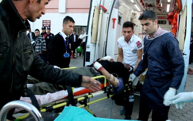 Des Turcs aident des blessés syriens après une explosion près de la frontière syro-turque, le 20 février 2014 (Crédit : Mehmet Engin/AFP)