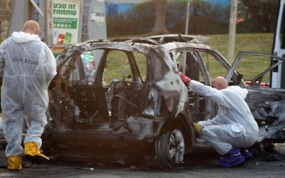 Des policiers enquêtent sur le véhicule, alors qu'une bombe a explosé dans la ville de Petach Tikva (Crédit :    Gideon Markowicz/Flash90)
