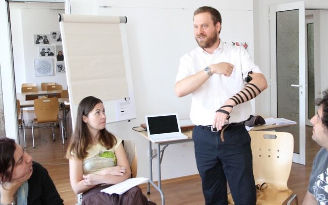 Le Rabbin Josh Ahrens qui montre comment mettre les téfilin lors d'un cours de conversion à Sofia, en Bulgarie (Crédit : Dianna Cahn/JTA)