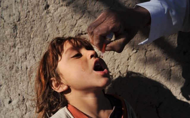 Une petite afghane reçoit un vaccin contre la polio d'un médecin lors d'une campagne de vaccination des enfants contre la polio dans la province de Nangarhar, 25 février 2014 (Crédit : AFP Photo/Noorullah Shirzada)