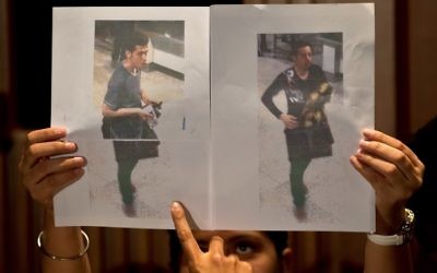 Un journaliste pointe du doigt la photographie du passager iranien Pouria Noor Mohammad Mehrdad (à gauche) alors qu'un policier malaisien montre les photographies des deux hommes ayant embarqué à bord du vol MH 370 avec des passeports européens volés, à Sepang (près de l'aéroport international de Kuala Lumpur), le 11 mars 2014 (Crédit : AFP PHOTO / MANAN VATSYAYANA)