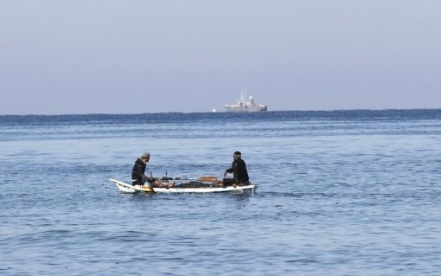 Des pêcheurs palestiniens assis dans leur barque à proximité du rivage de Rafah, au sud de Gaza ; un bateau de police israélien apparaît au loin, le 26 mars 2014. (Crédit : Said Khatib/AFP)