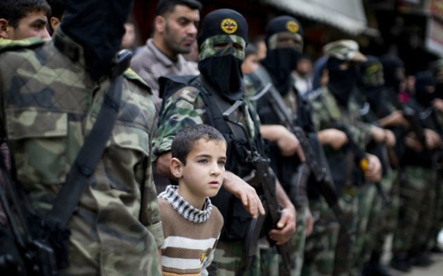 Un jeune garçon se tient au milieu de Palestiniens du Jihad islamique, dans la bande de Gaza (Crédit : Mahmud Hams/AFP) Un jeune garçon se tient au milieu de Palestiniens du Jihad islamique, dans la bande de Gaza (Crédit : Mahmud Hams/AFP)