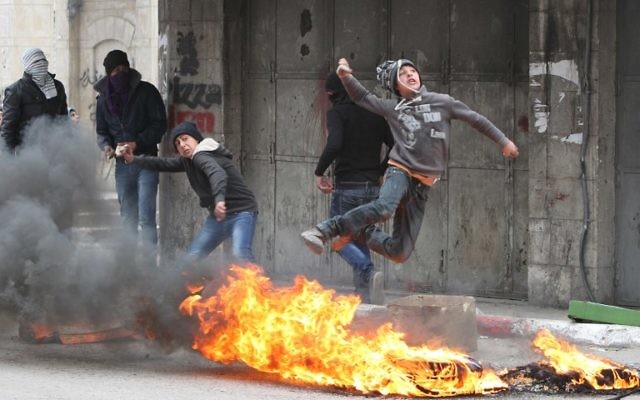 Des Palestiniens jettent des pierres sur les forces de sécurité israéliennes à Hébron le 17 mars 2014 (Crédit : AFP/Hazem Bader) Des Palestiniens jettent des pierres sur les forces de sécurité israéliennes à Hébron le 17 mars 2014 (Crédit : AFP/Hazem Bader)