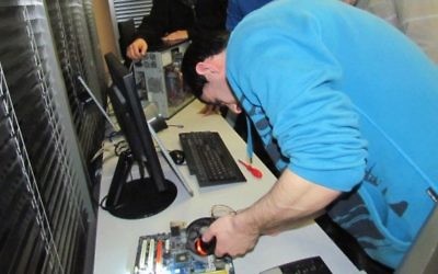 Un étudiant de John Bryce travaille à réparer un ordinateur, sans doute destiné à être envoyé chez un enfant nécessiteux (Crédit : autorisation)
