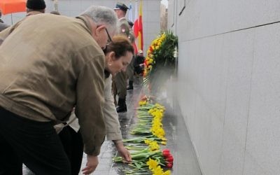Des gens posent des fleurs à Umschlagplatz dans le ghetto de Varsovie, un monument à la mémoire des victimes de l'Holocauste (Crédit : Ruth Ellen Gruber/JTA)