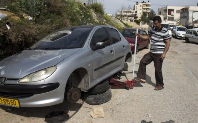 A titre d'illustration: un Palestinien change les pneus de sa voiture après une attaque de type "prix à payer" en mars 2014 (Crédit : Ahmad Gharabli/AFP)