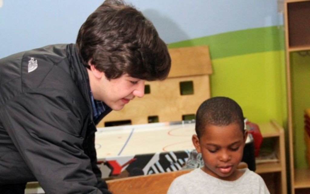 Nicholas Lowinger aidant un enfant à récupérer des nouvelles chaussures (Crédit : JTA) Nicholas Lowinger aidant un enfant à récupérer des nouvelles chaussures (Crédit : JTA)