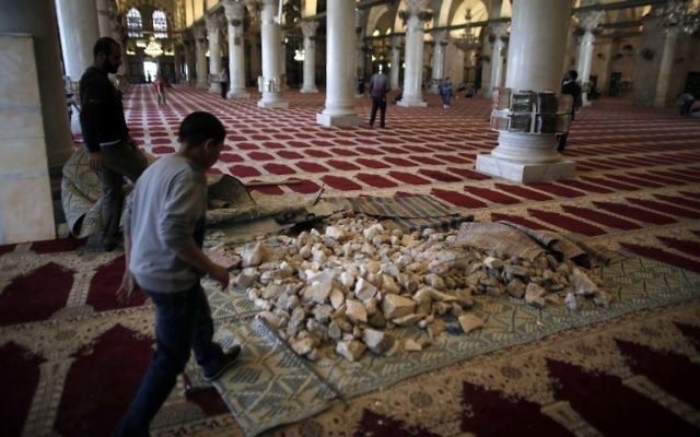Des pierres stockées à l'intérieur de la mosquée d'Al-Aqsa, qu'un employé tente de nettoyer, en 2014. (Crédit : AFP/Ahmad Gharabli)