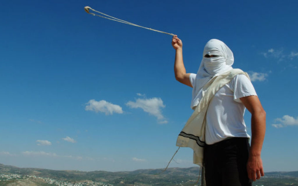 Un habitant masqué de Yitzhar, en Cisjordanie, lance des pierres avec une fronde, le 19 mai 2013. (Crédit : Mendy Hechtman/Flash90) Un habitant masqué de Yitzhar, en Cisjordanie, lance des pierres avec une fronde, le 19 mai 2013. (Crédit : Mendy Hechtman/Flash90)
