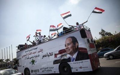 Une affiche de Sissi sur un bus rempli de supporters avec des drapeaux égyptiens en mai 2014 (Crédit : MAHMOUD KHALED/AFP)