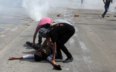 Des Palestiniens aident un ami blessé près de la prison d'Ofer, à Beitunia (Crédit : Abbas Momani/AFP)