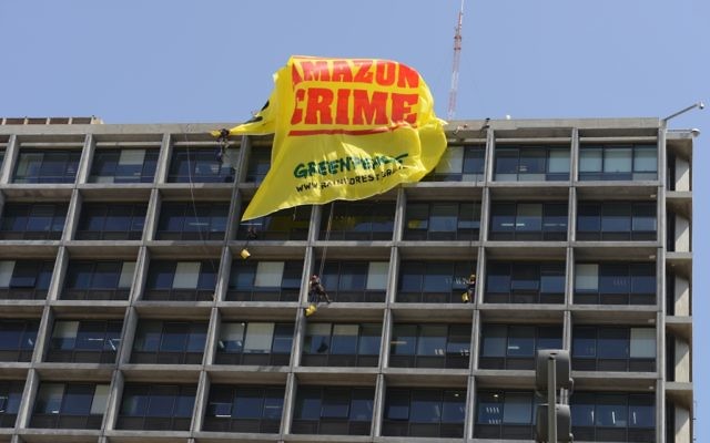 Des activistes de Greenpeace sur un toit d'un immeuble à Tel Aviv pour accrocher une banderole (Crédit : Greenpeace/autorisation) Des activistes de Greenpeace sur un toit d'un immeuble à Tel Aviv pour accrocher une banderole (Crédit : Greenpeace/autorisation)