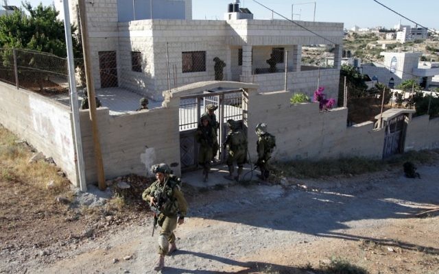 Une maison dans le village de Tafoh, près de Hébron, inspectée par des soldats israéliens (Crédit : AFP/ HAZEM BADER)