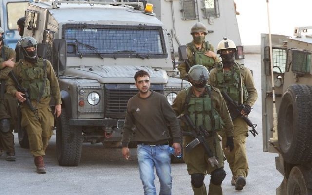 Des soldats israéliens détiennent un civil palestinien près de Hébron (Crédit : Hazem Bader/AFP) Des soldats israéliens détiennent un civil palestinien près de Hébron (Crédit : Hazem Bader/AFP)