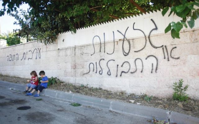 Des enfants assis près d'un mur où il est inscrit en hébreu : "racisme ou assimilation", "les Arabes dehors" à Abu Ghosh (Crédit : Flash90) Des enfants assis près d'un mur où il est inscrit en hébreu : "racisme ou assimilation", "les Arabes dehors" à Abu Ghosh (Crédit : Flash90)