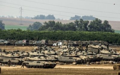 Soldats israéliens situés près de tanks Merkava à proximité de la bande de Gaza (Crédit : AFP/JACK GUEZ)